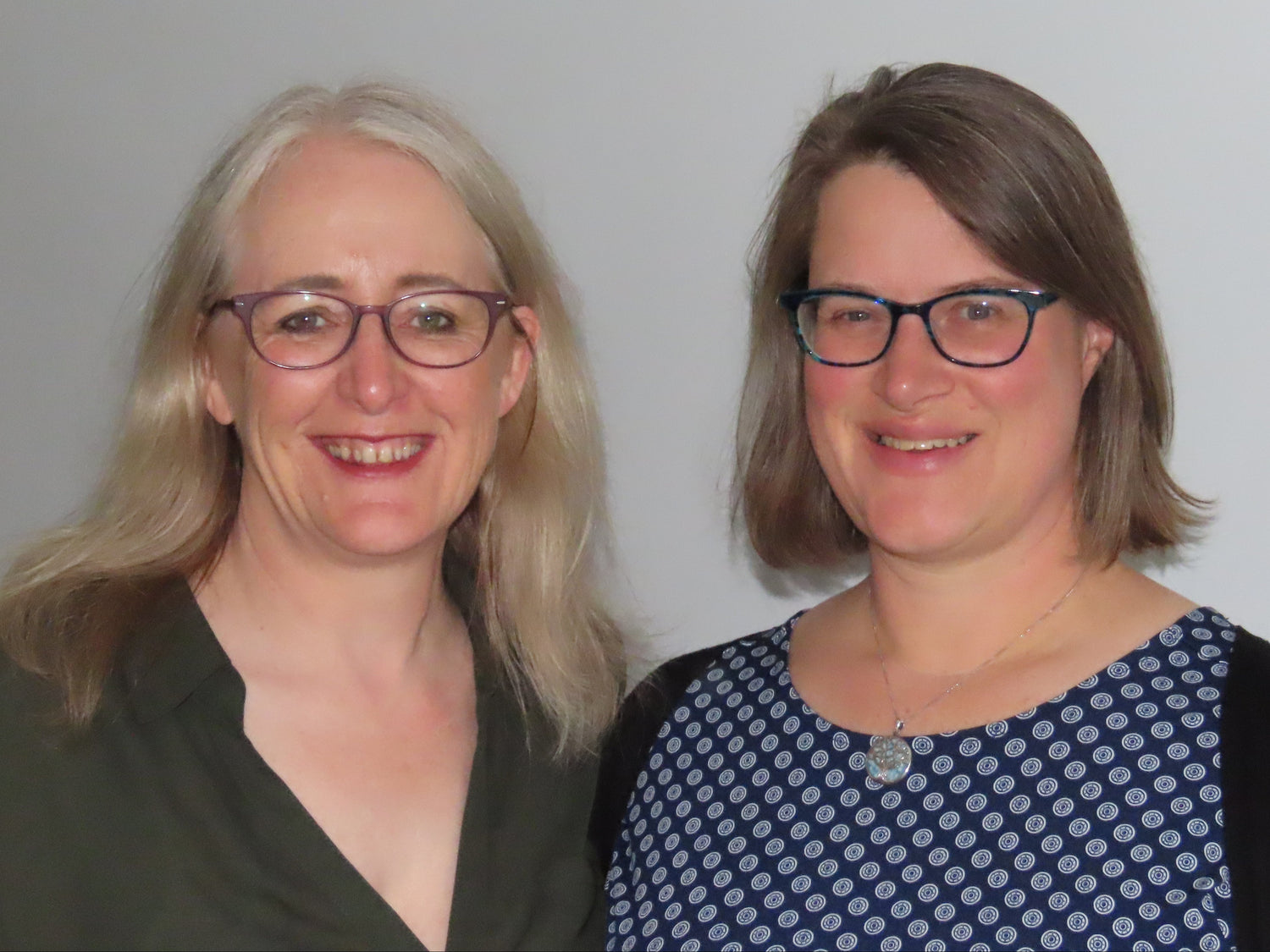 Two women, Fiona Brooker and Mia Bennett, with glasses standing side by side against a plain background